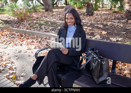 African american executive working outdoors, enjoying technology during autumn Stock Photo