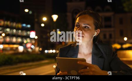 Urban woman with computer tablet on city street at night. Stock Photo