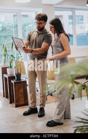 Colleagues Discussing Data on a Tablet in a Bright Office Space Stock Photo