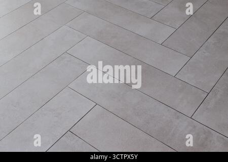 Grey rectangular tile texture in herringbone pattern imitating natural stone. Stock Photo