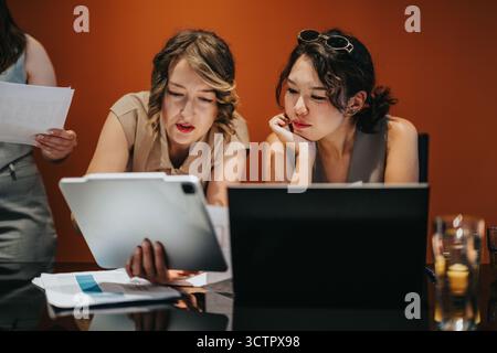 Two professional women collaborating on a business project in a modern office Stock Photo