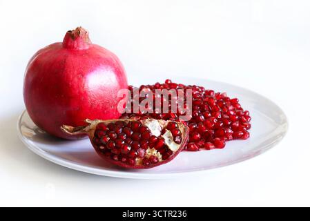Fresh pomegranate fruit and pomegranate seeds on a white background. Healthy food. Close-up. Stock Photo