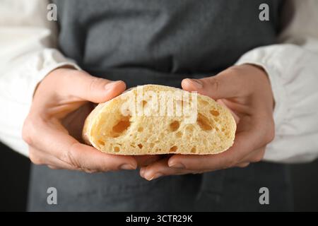 Woman holding half of fresh crispy ciabatta, closeup Stock Photo