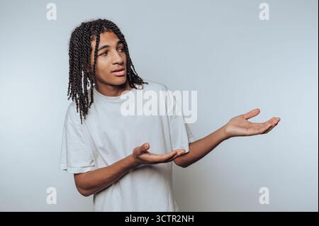 Young man with braided hair gesturing in confusion Stock Photo