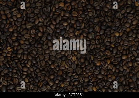 Close-up texture of roasted coffee beans. Dark brown background made of aromatic coffee seeds, top view. Stock Photo