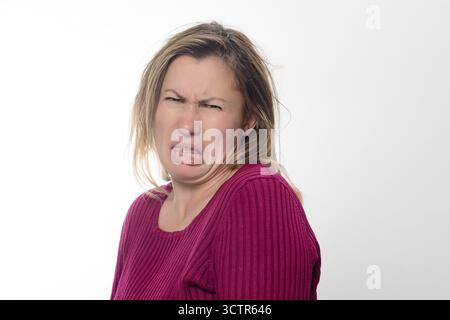 Woman making a disgusted face against white background. Stock Photo