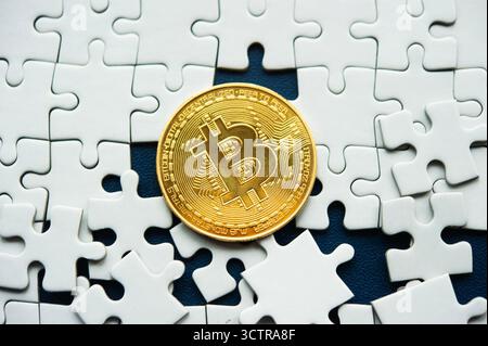 Bitcoin coin among white puzzle pieces symbolizing cryptocurrency as a key to the digital financial puzzle Stock Photo