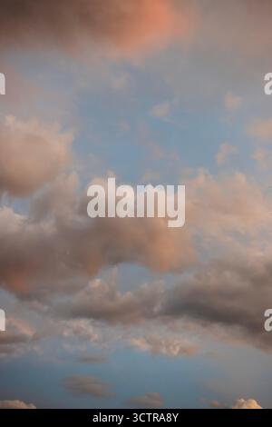 Soft pastel-colored clouds in a blue sky during sunset creating a tranquil and dreamy atmosphere Stock Photo