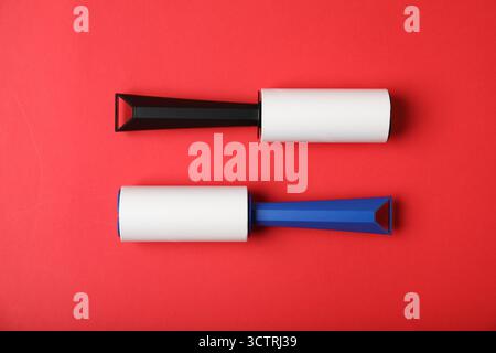 Two lint rollers on red background, flat lay Stock Photo