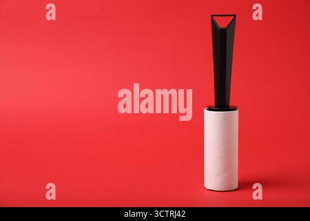 One lint roller on red background, space for text Stock Photo