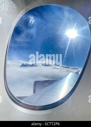 An air passenger's view though the aircraft porthole or window above the blue sky with scattered clouds over the Indian Ocean towards Western Australi Stock Photo