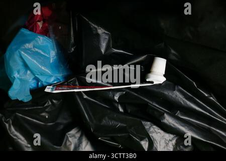 Empty toothpaste tube on plastic trash bag Stock Photo