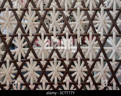 Star weave rattan with dark brown and cream strands in contrasting pattern. Close-up. Copyspace. Stock Photo