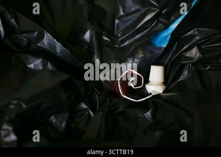 Empty toothpaste tube on plastic trash bag Stock Photo