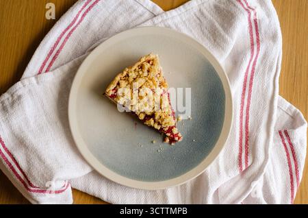 Top view of sbriciolata crumble pie slice with plum jam. Homemade rustic dessert with buttery crumbs. Perfect for autumn baking and Christmas season Stock Photo