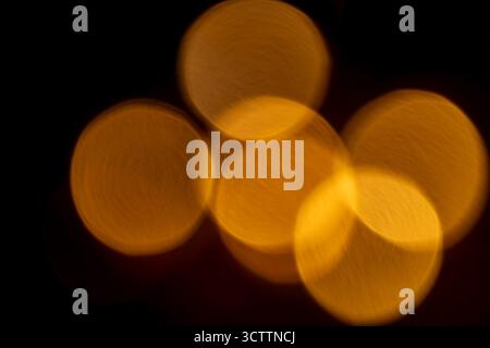 Defocused orange bokeh on black background — warm glowing orbs and soft golden highlights; abstract blurred backdrop suitable for wallpaper and stock Stock Photo