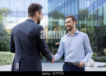 Businessmen shaking hands outdoors, completing a successful deal and agreement, representing partnership, collaboration, and trust in a modern corporate environment Stock Photo