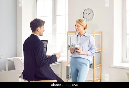 Positive Business Colleagues Chatting During Break In Office And Drinking Coffee Stock Photo