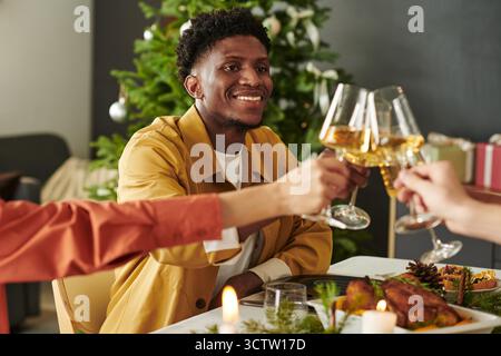 Young Black Man Smiling While Toasting Wine Glasses during Holiday Celebration Stock Photo