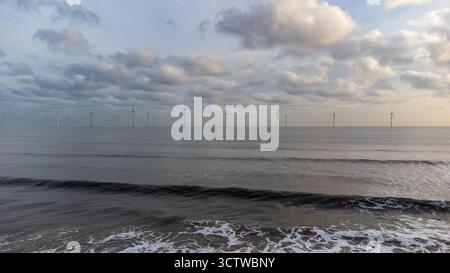 View of offshore wind turbines standing in calm sea waters at sunrise Stock Photo