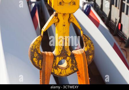 Large yellow double sided cargo crane hook with load straps on it under load Stock Photo