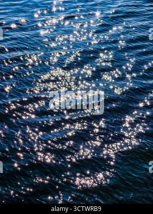 Sparkling Sunlight Reflections on Deep Blue Ocean Water Surface - Natural Light Bokeh Effect for Meditation and Relaxation. Nature Background Stock Photo