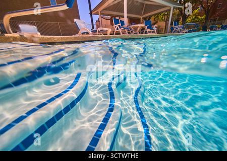 Underwater Pool Steps Sunlit Water and Neighborhood Patio Seating Stock Photo