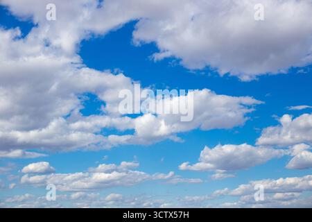 Fluffy white cumulus clouds float across a blue sky, a picturesque celestial landscape. Stock Photo