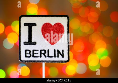 I LOVE BERLIN patch on a rainbow bokeh background. Colorful blurred lights create a festive atmosphere, ideal for Germany travel and Christmas themes. Stock Photo