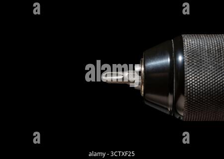 Chuck for cordless screwdriver with bit for unscrewing or screwing screws on black background, close up. Nozzle for screwdriver, attachment bit, macro Stock Photo