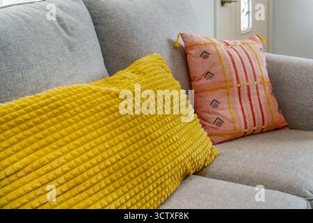 Close-up of colorful, textured, and printed pillows on a gray sofa couch. Stock Photo