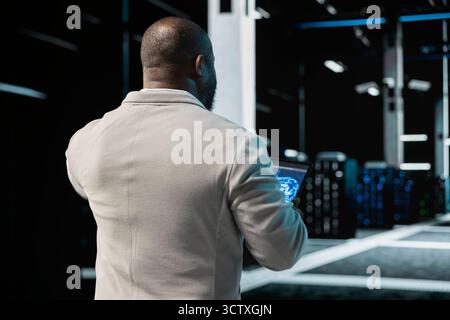 Data center engineer using AI technology on tablet to enhance operational effectiveness. Server hub worker utilizing artificial intelligence technology to predict future infrastructure needs Stock Photo