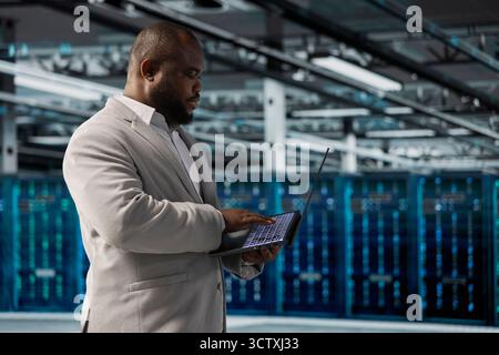 Data center employee running predictive maintenance scans, fixing network issues affecting rigs performance. Technician running system diagnostic tests, tracking resource utilization Stock Photo