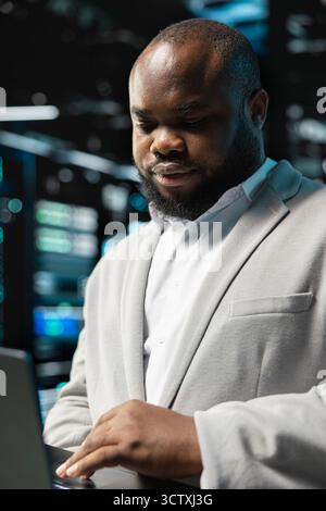 Close up of data center programmer using laptop to protect servers from exploitable software vulnerabilities, auditing systems. Server hub worker looking for bugs slowing down equipment Stock Photo