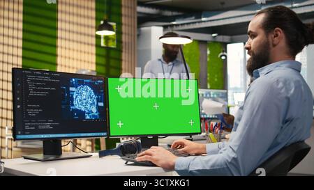 Technician in office using green screen PC, automating repetitive tasks with AI scripts. IT expert using artificial intelligence tech on mockup computer to speed up feature implementation, camera A Stock Photo