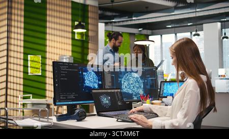 Junior developer in office integrating AI machine learning systems to streamline workflows. Young employee uses neural networks artificial intelligence, technology overload concept, camera A Stock Photo