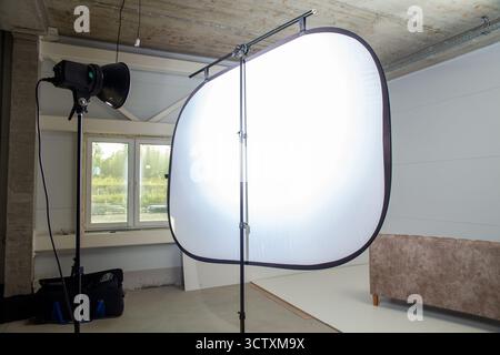 Photo setup in a furniture factory corner with studio flashes and a large softbox for soft, professional lighting of sofas and armchairs. Stock Photo