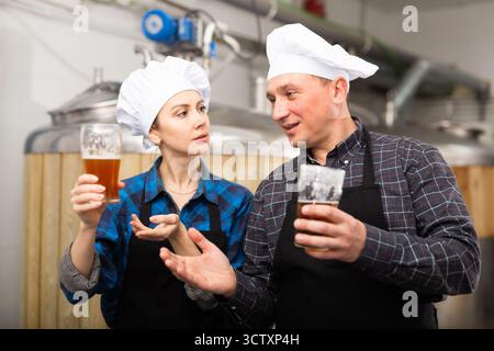 Man and woman brewers talking about beer in factory Stock Photo