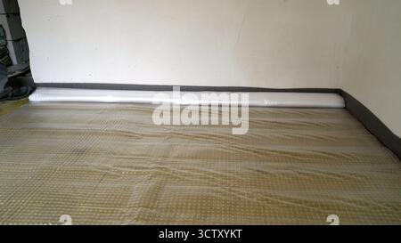 Installing waterproof underlayment membrane over the subfloor, preparing for new flooring installation during home renovation Stock Photo