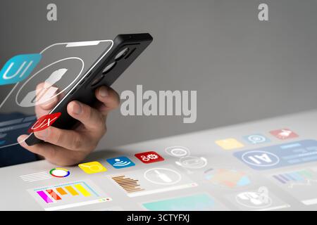 Hand holding smartphone with digital interface showing UI UX design, data analytics, and AI technology concept, representing mobile app development, i Stock Photo