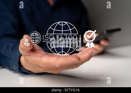 Hand holding digital icon of ISO 27001 information security management system certification, symbolizing data protection, cybersecurity, business comp Stock Photo