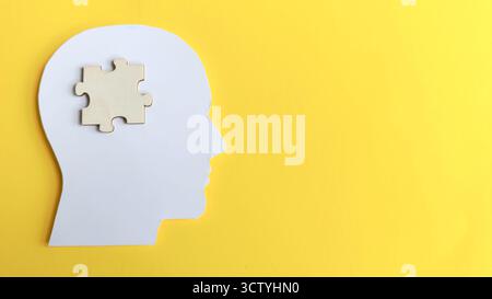 Human head silhouette with a wooden jigsaw puzzle piece inside, symbolizing problem solving, finding the solution, mental health, and missing knowledg Stock Photo