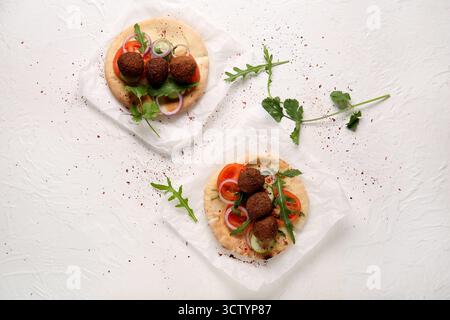 Baking paper of delicious pitas with falafel and fresh vegetables on white background Stock Photo