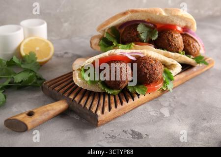 Wooden board of delicious pitas with falafel on grey background Stock Photo