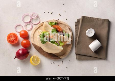 Wooden plate of delicious pitas with falafel and fresh vegetables on white background Stock Photo