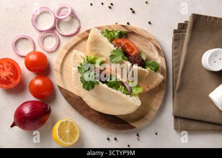 Wooden plate of delicious pitas with falafel and fresh vegetables on white background Stock Photo