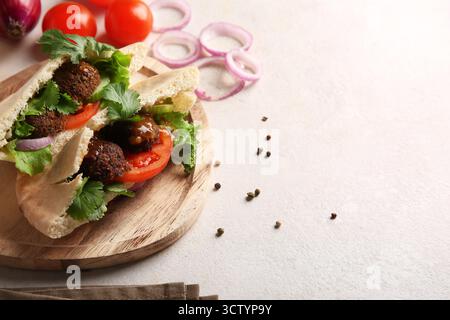 Wooden plate of delicious pitas with falafel and fresh vegetables on white background Stock Photo