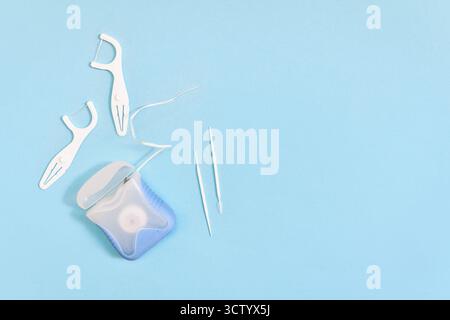 Dental floss and toothpicks on blue background with copy space. Oral hygiene products Stock Photo