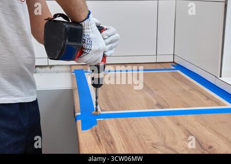 repairman using electric drill and installation new modern kitchen Stock Photo