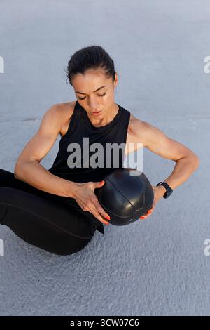 High-angle view of young, muscular female athlete doing core exercises with a medicine ball Stock Photo